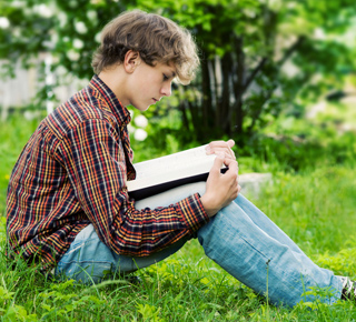 Boy sitting outside and reading a book
