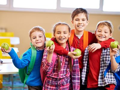 Happy primary school children, each holding an apple