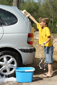 Young boy cleaning the family car