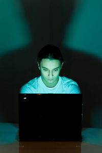 Teenage boy using his laptop late at night