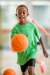 Happy young boy playing basketball