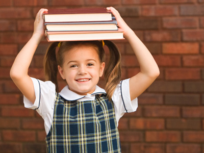 Young girl balancing school books on her head