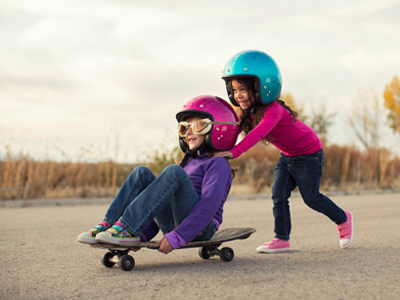 Two young friends playing on a skateboard