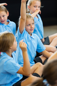 Pupils in primary school class raising their hands