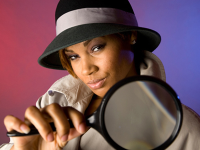 Woman dressed as inspector holding a magnifying glass