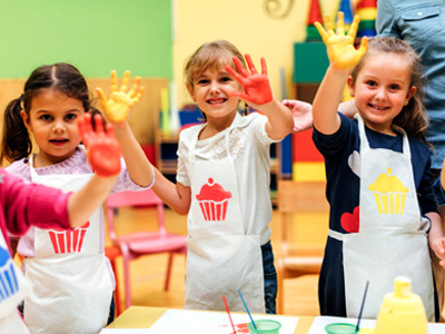 Young girls in nursery school painting with their hands