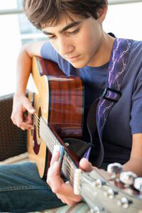 Teenage boy learning to play the guitar