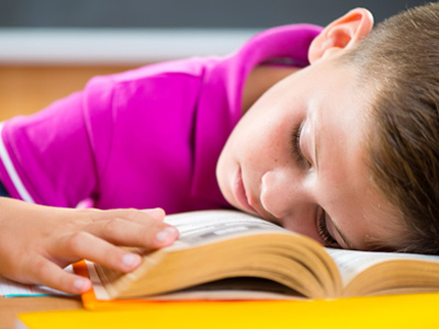 Sleeping schoolboy using textbook as a pillow