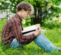 Boy sitting on grass and reading a book
