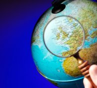 Magnifying glass examining a globe of the world