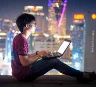 Boy using a computer with city skyscape in the background