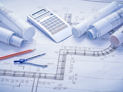 Close-up of professional technical blueprints with a calculator and drawing compass for 11 plus Maths diagnostic testing.