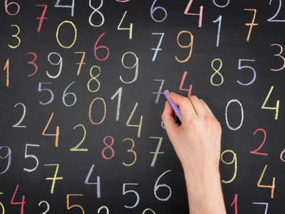 Hand writing many colourful numbers on blackboard