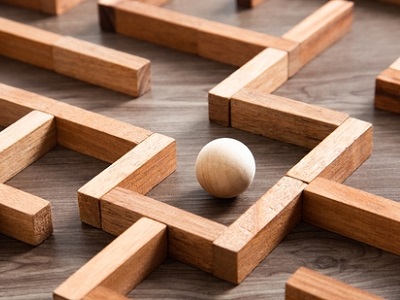 Close-up of a wooden labyrinth puzzle with a silver ball, representing the spatial logic and navigation required for 11 plus Non-Verbal Reasoning.