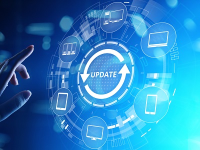A hand reaching towards a glowing digital interface with the word “Update” in the centre, surrounded by icons of laptops, tablets, and smartphones.