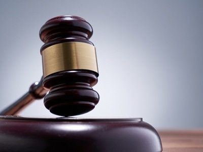 A wooden judge’s gavel resting on a block with a soft grey background, representing justice or decision-making.