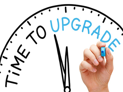A hand drawing the word “Upgrade” on a clock face with the phrase “Time to Upgrade” written across it, symbolising progress and improvement.