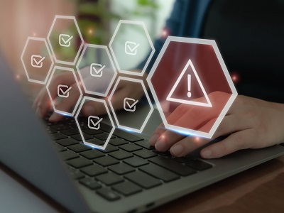 A person typing on a laptop with digital icons showing checkmarks and a warning triangle, representing success and error in AI or automated systems.