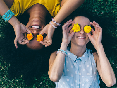 Two friends lying on grass with dandelions