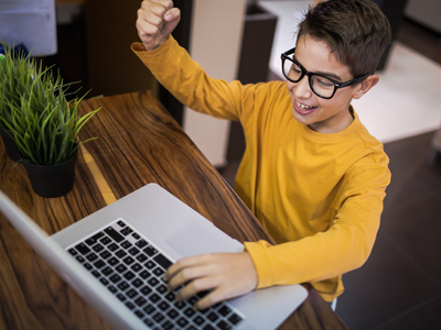 Boy raising fist in success on laptop