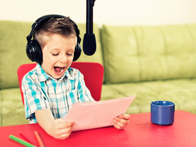 Boy reading aloud into microphone with headphones