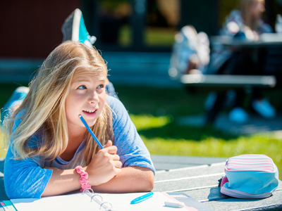 Girl writing in notebook sitting on grass