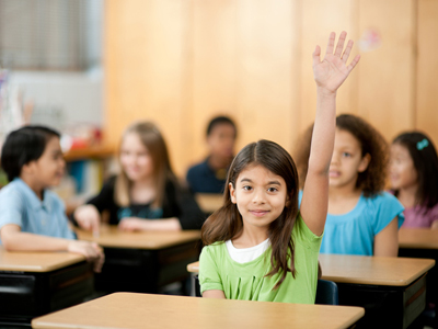 Girl with hand raised in a classroom