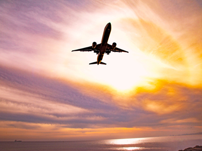 Silhouette of airplane flying in sunset sky