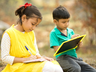 Boy and girl writing and sitting outside