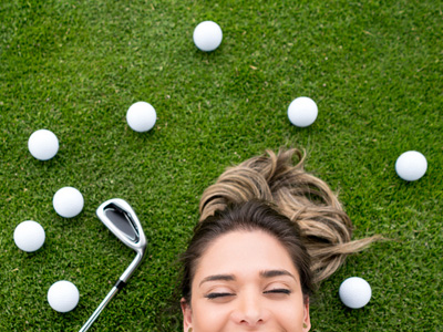 Female golfer lying on grass smiling