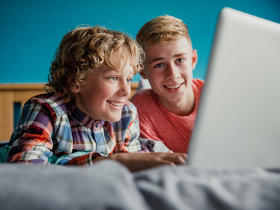 Children in bedroom writing on laptop