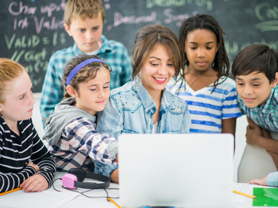 Teacher in class surrounded by kids