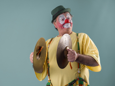 A happy clown banging cymbals together