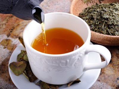 A cup of tea being poured from a pot