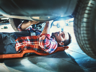 Garage mechanic working under a car