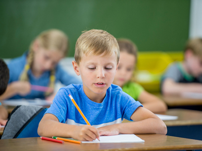 Grade 5 boy writing at school desk