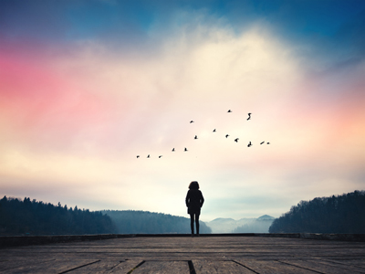 Silhouette of person by a lake at sunrise