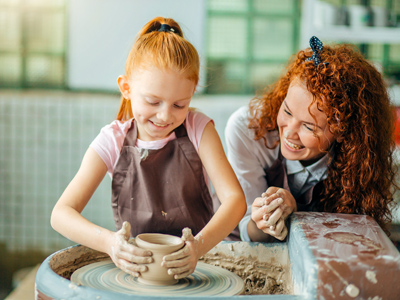 Child and teacher making clay pot