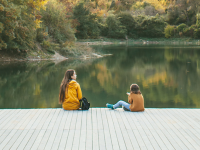 Children sat beside smooth lake