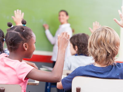 Class of children with raised hands