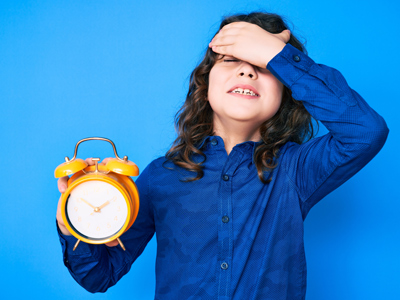 Grumpy child holding alarm clock