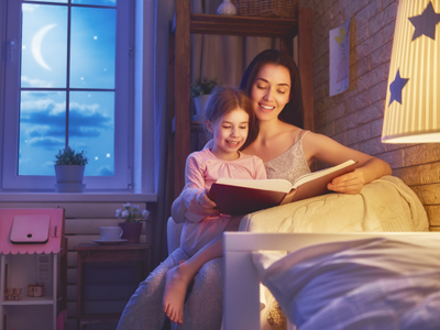 Child reading bedtime story with mother