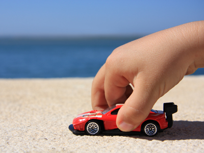 A child's hand playing with a toy car