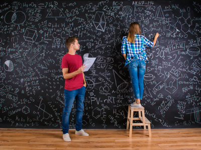 Two students doing advanced maths on a blackboard