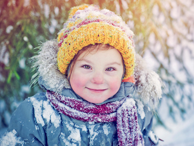Young girl in woolly hat and scarf in snow