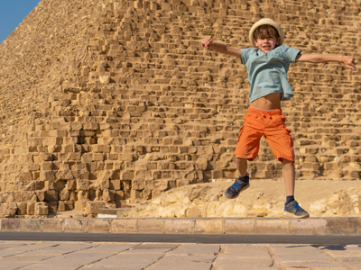 Happy child jumping in front of the pyramids