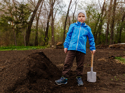 Child helping in garden with a spade