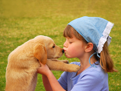 Child kissing her puppy