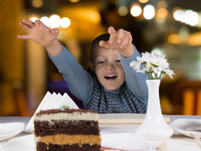 Child reaching for chocolate cake