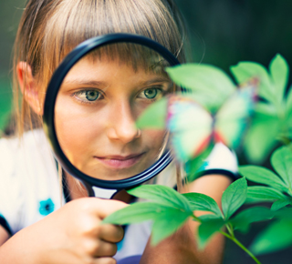 Young scientist examining a plant with a magnifying glass